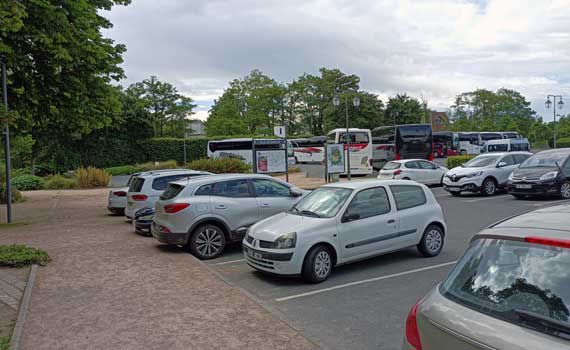 Vegetation, large parking lot, cars and buses